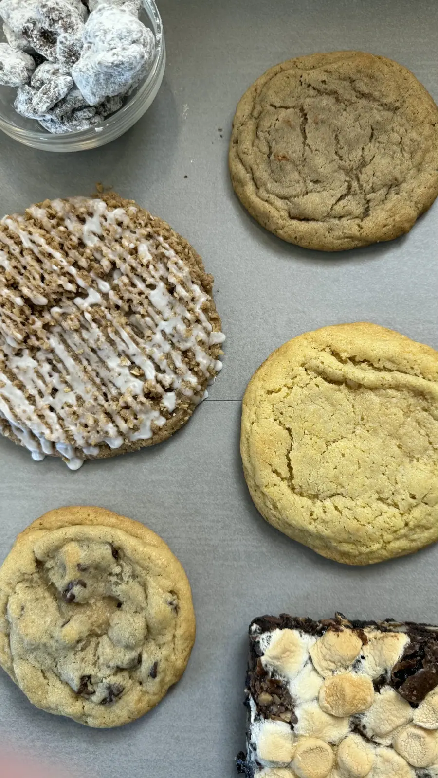 Cookies, a brownie and puppy chow laid out